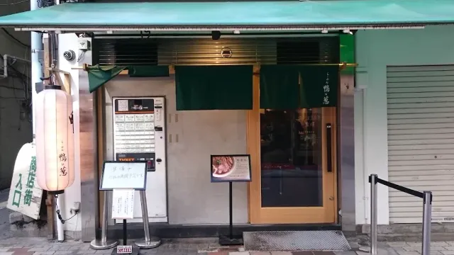 חזית קטנה עם סוכך ירוק, וילון בד ירוק, מכונת כרטיסים ופנס לבן