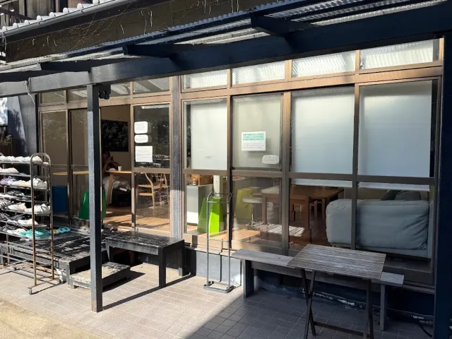 חזית כהה עם מסגרות זכוכית, ספסל עץ וכניסה פתוחה לחדר פנימי