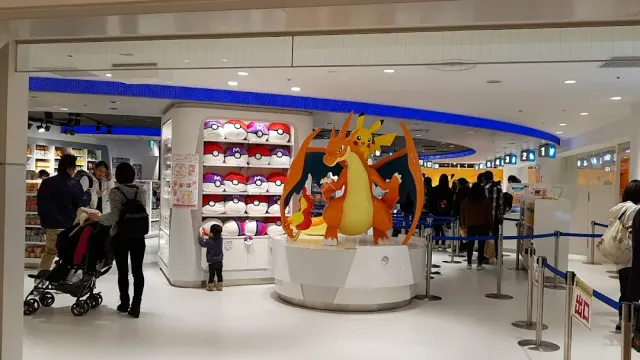 חנות מוארת עם פסל דמות דרקון כתומה במרכז ומדפי בובות סביב