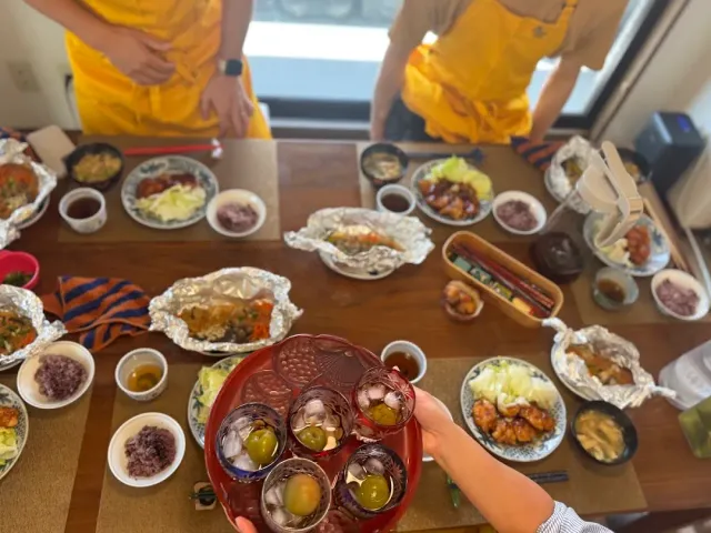 שולחן עמוס מנות ביתיות בקערות קטנות, יד מחזיקה מגש אדום עם קינוחים